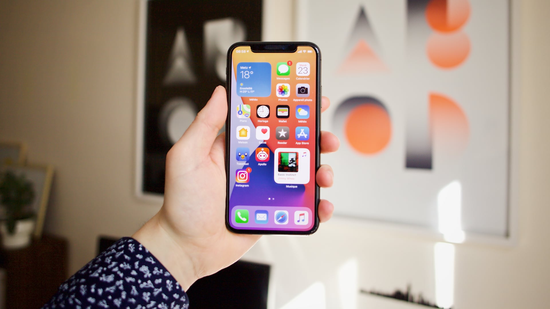 iPhone 14 Pro Max in a woman's hand, set against a wall with paintings